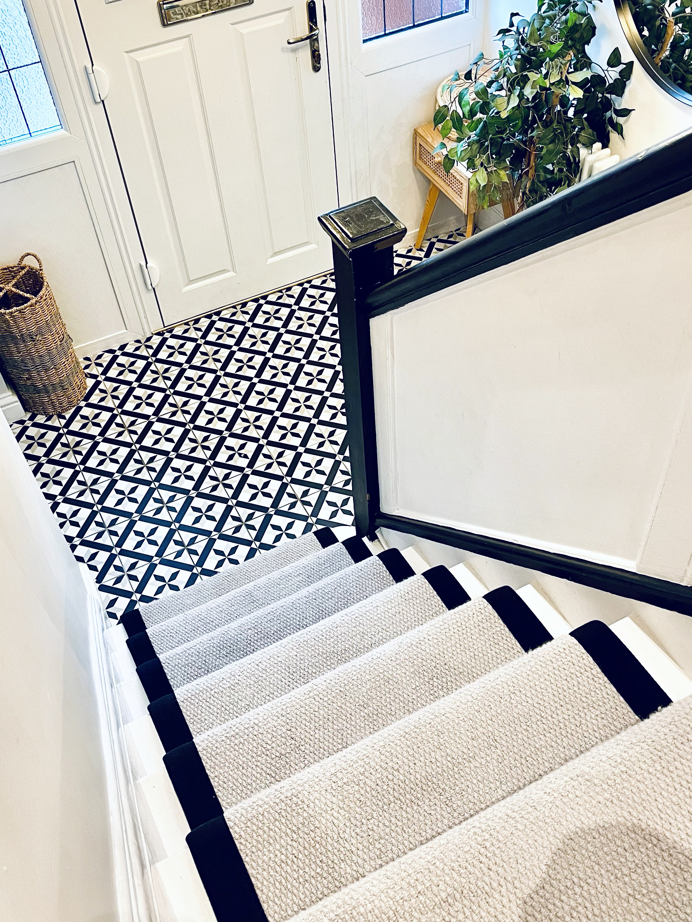 black and white tiled hallway with cream and black stair runner